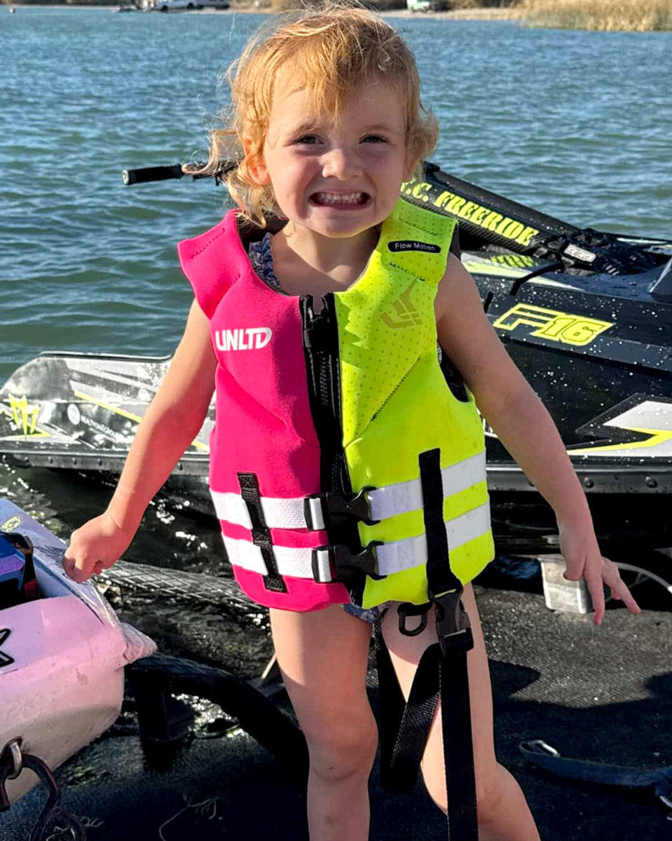 Child Neo Life Vest by Unlimited PWC, yellow and pink flotation vest with adjustable straps, designed for safety and comfort in water activities.